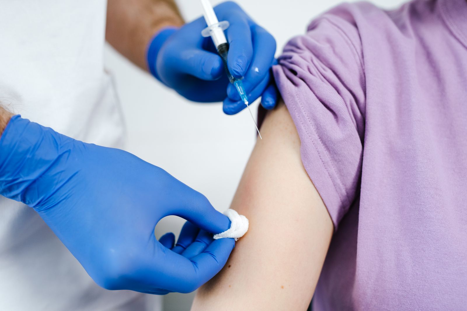 Close-up of a health professional administering a vaccine injection to a patient's arm.